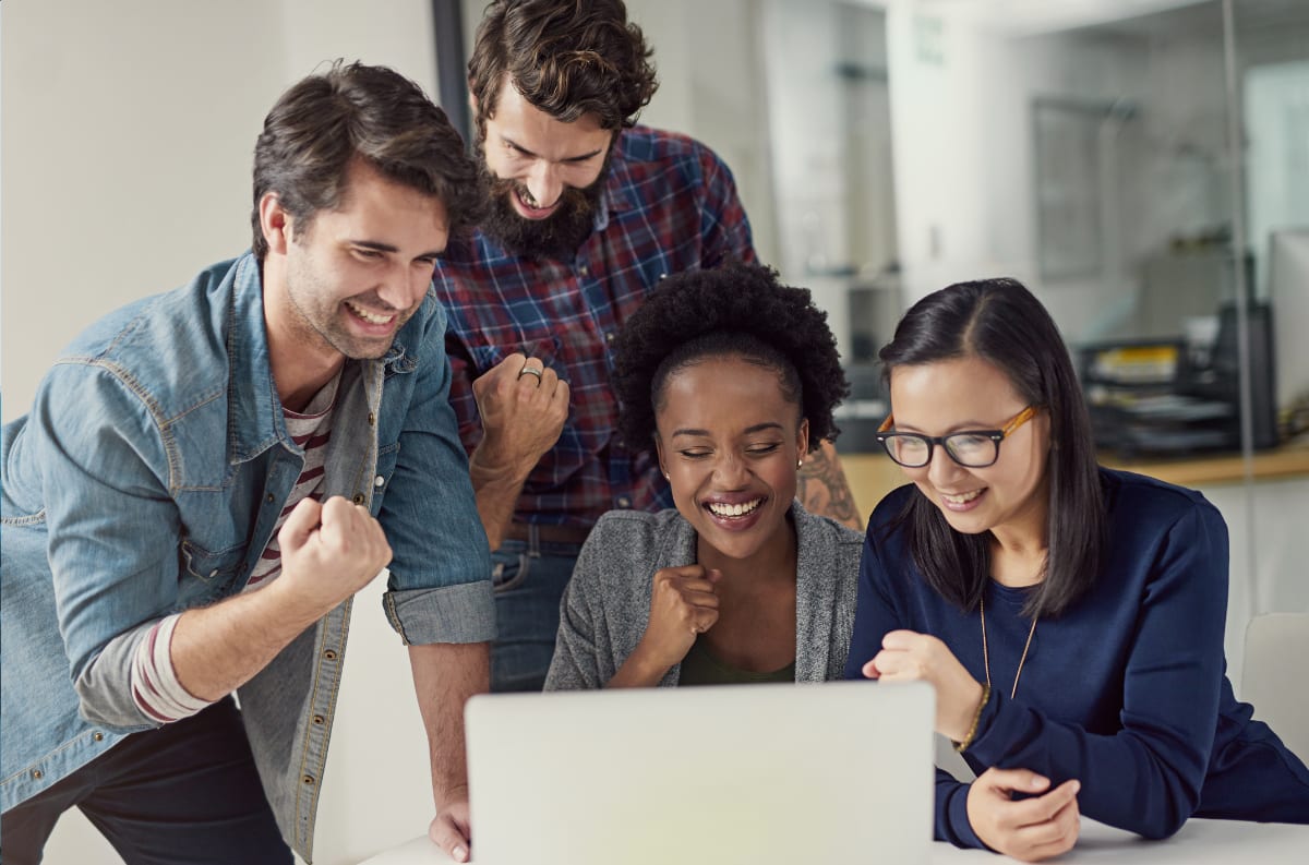 Lending team celebrating around a laptop after a loan approval