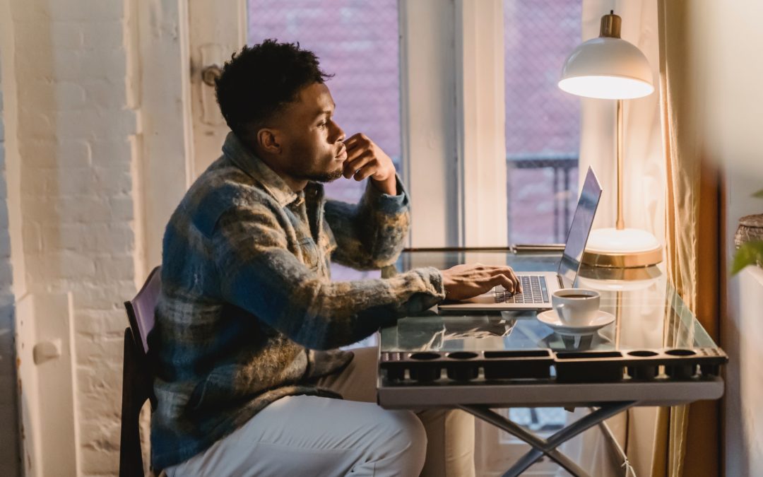 Thoughtful young man thinking at laptop with coffee cup choice loan servicing software